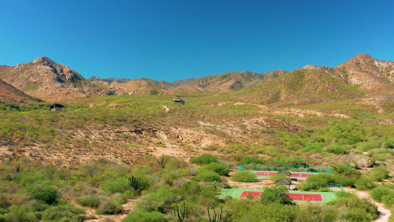 Wide desert hillside view with tennis courts at the bottom.