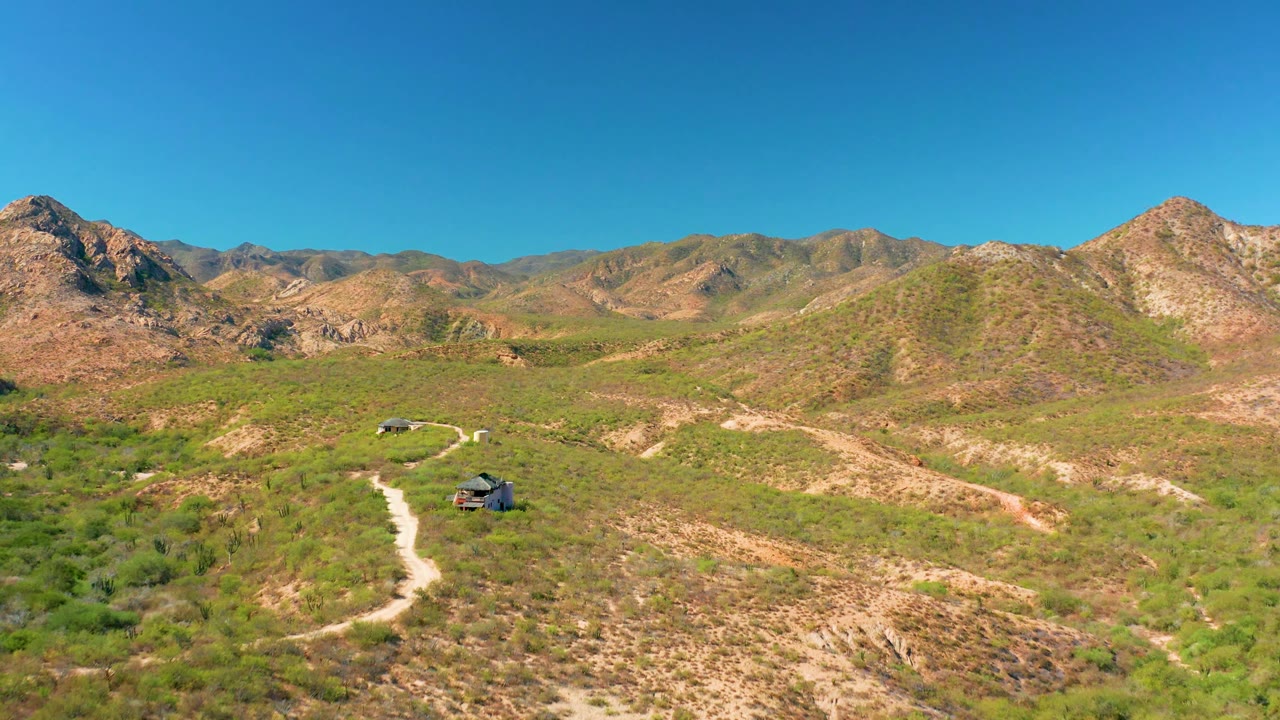 Wide desert mountain landscape with vehicles on a winding path.