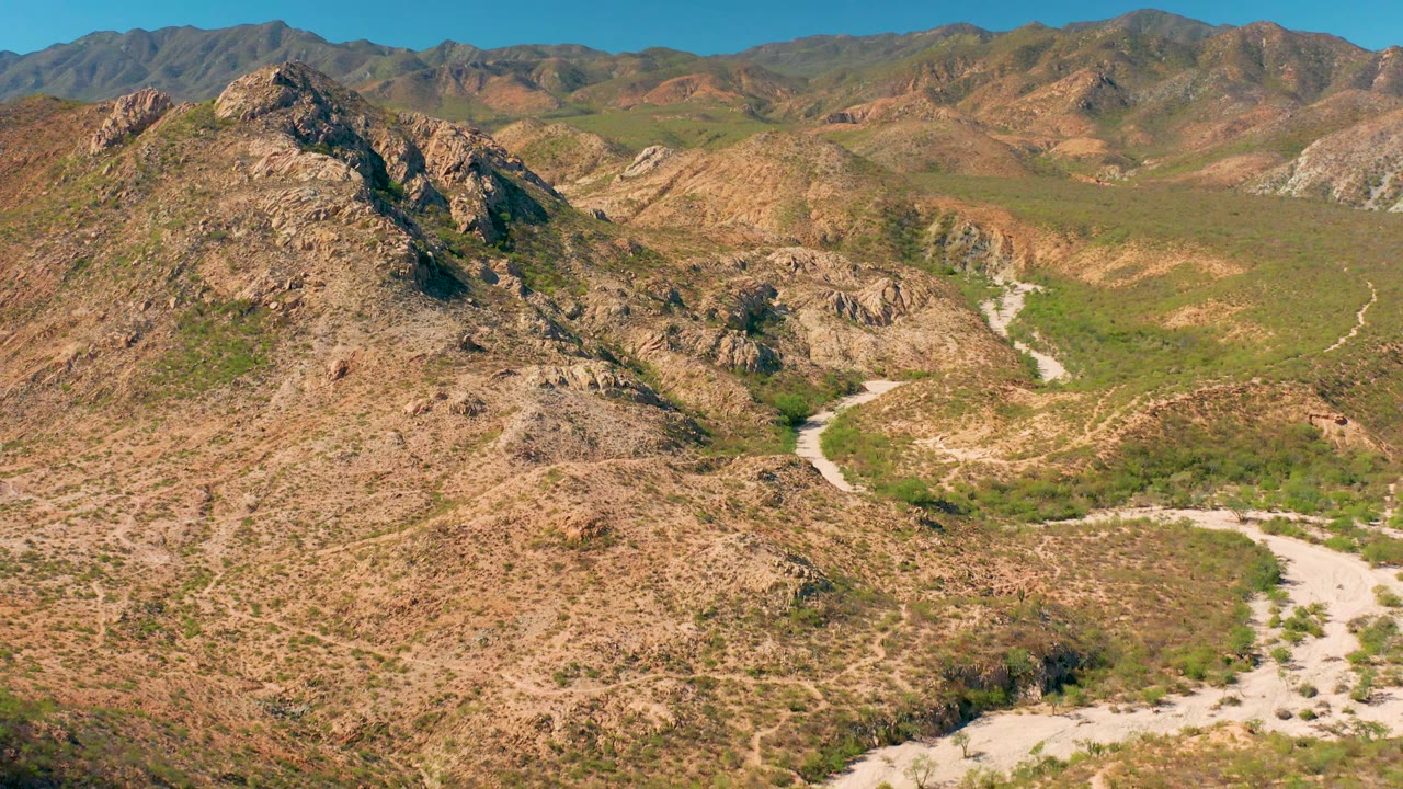 Aerial mountain landscape with dirt road crossing rocky arid terrain.