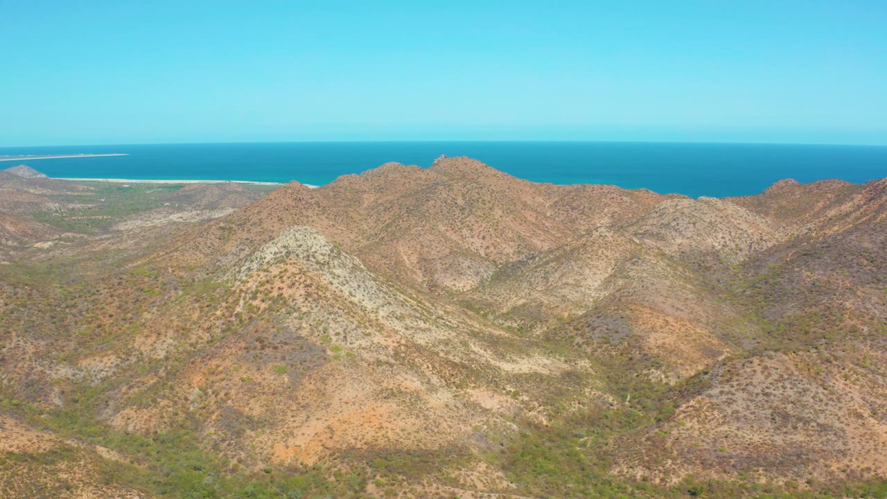 Aerial mountain landscape with sea and horizon behind the ridges.