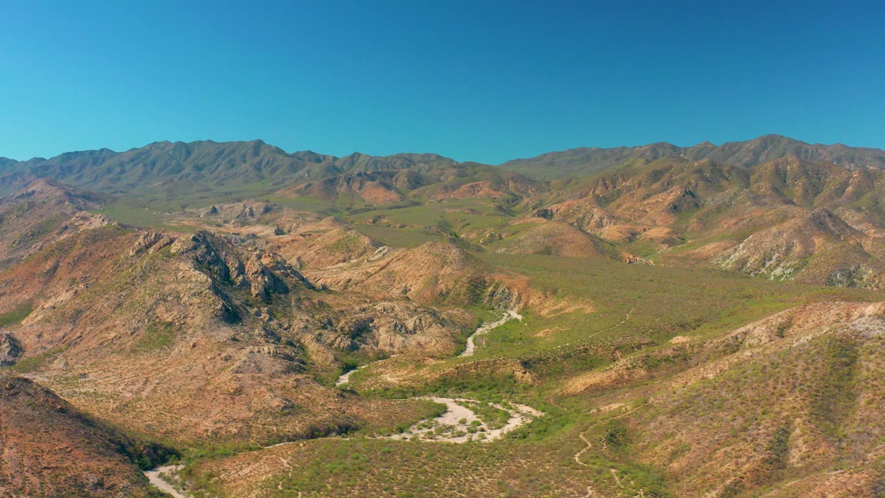 Aerial view over dry hills with a road crossing the valley