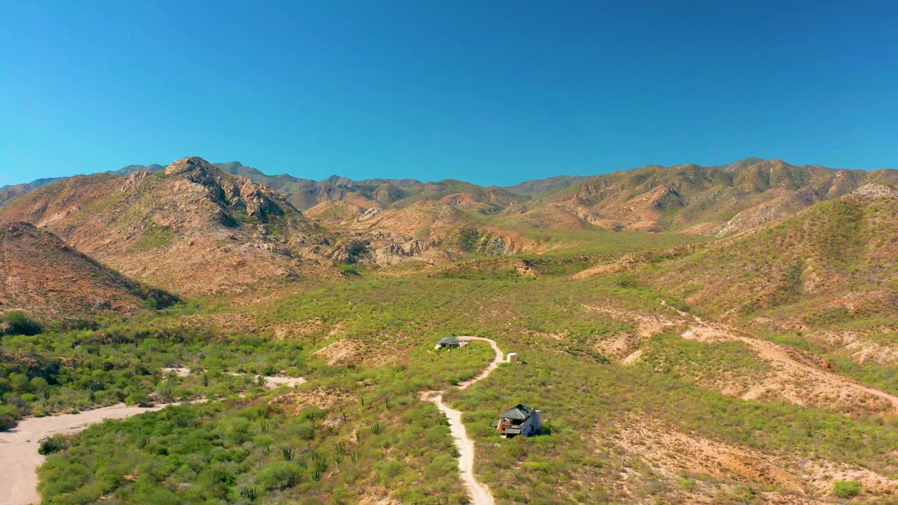 Small vehicle on a pale road below rocky mountains
