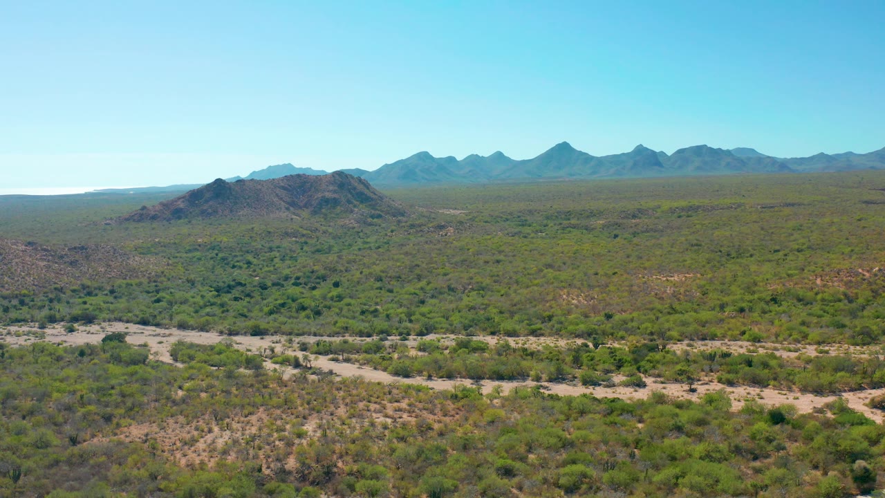 Mountain range beyond low desert hills and brush