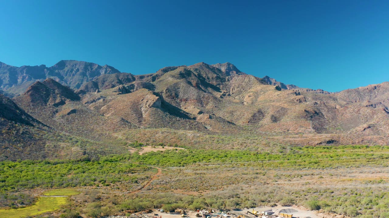At 0:02, the wide Loreto landscape shows a clear sky over layered rocky hills, scrubby green valley patches, dry terrain, and no visible people.