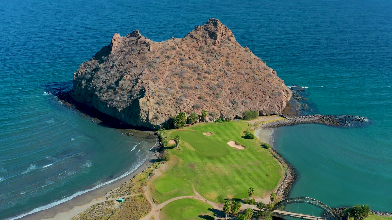 Loreto, Baja California Sur aerial frame with the rocky island set against open water and the golf course filling the lower portion, with no visible people.