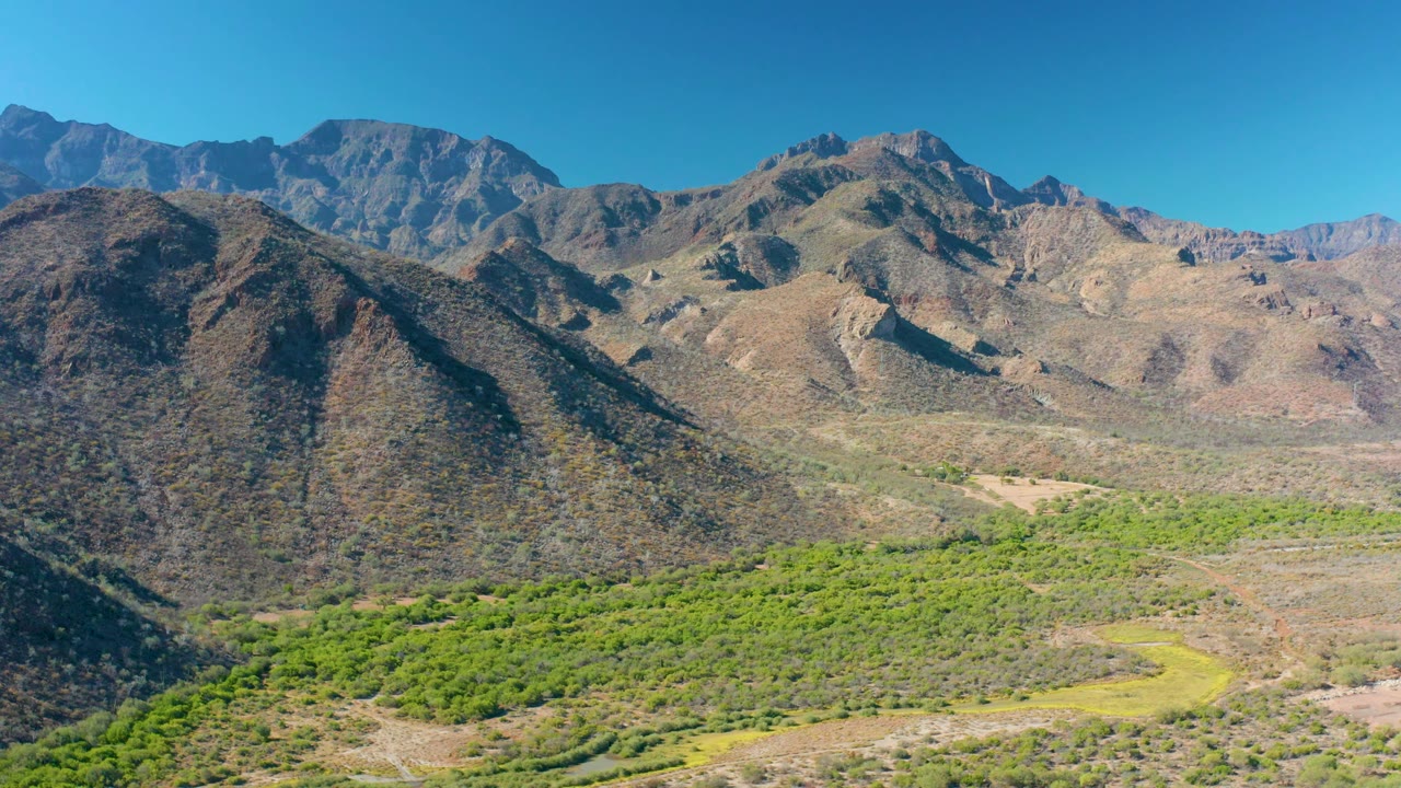 Wide aerial view of rugged mountains and green vegetation.