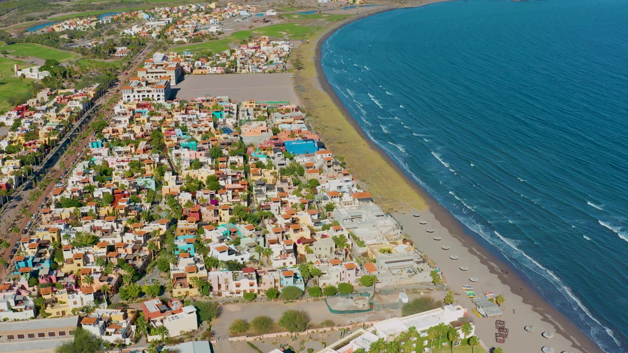Aerial coastal town view with beach curving along blue water.