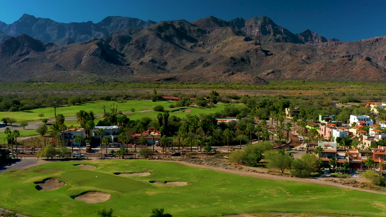 Golf course and residential edge below dark mountain slopes.