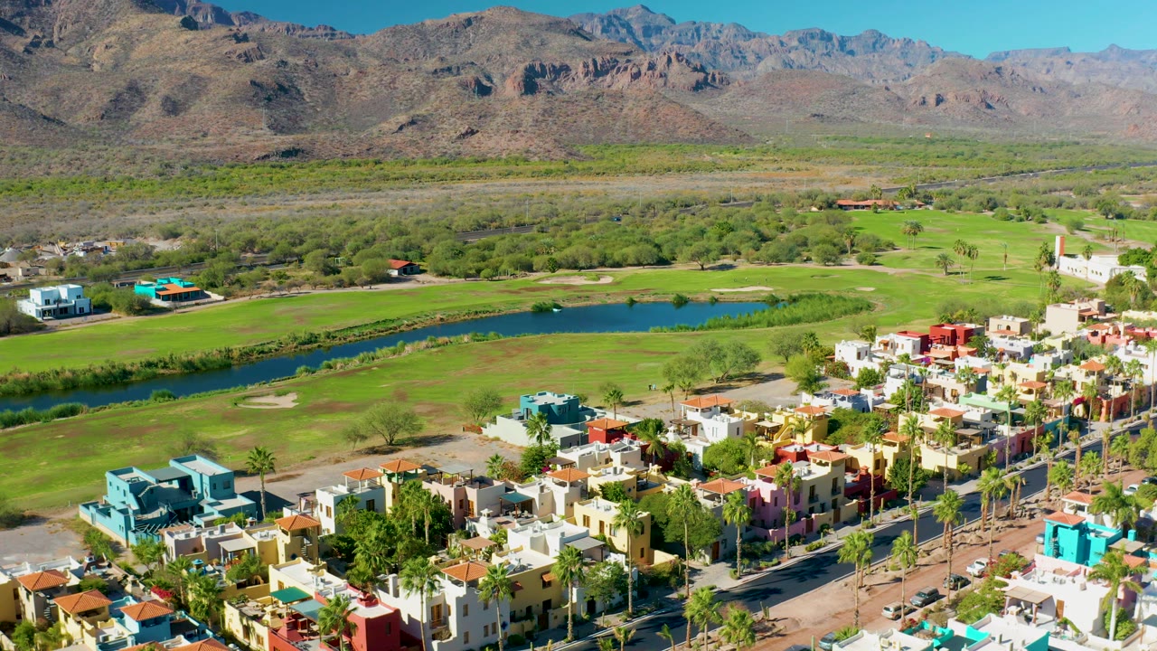 Wide drone view of golf course water and homes near mountains