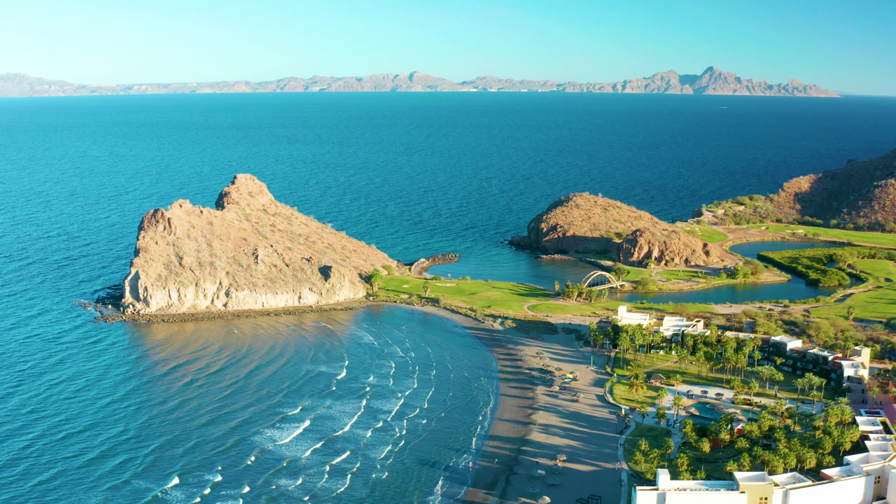 Rocky coastal point with beach waves and landscaped shore