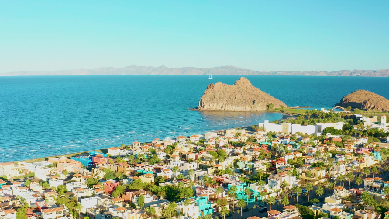 Aerial view over Loreto rooftops toward beach, ocean, and rocky islands