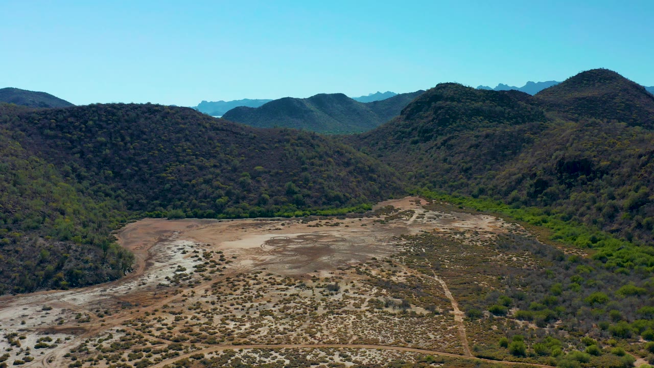 Arid valley and forested hills with distant ridges.