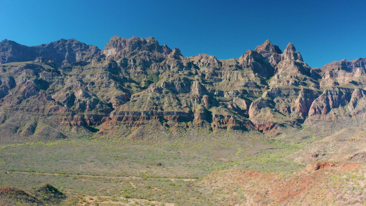 Wide rocky mountain range above a sparse desert valley.