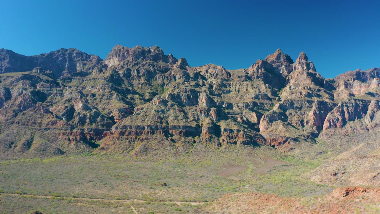 Wide desert mountain range under a clear blue sky.