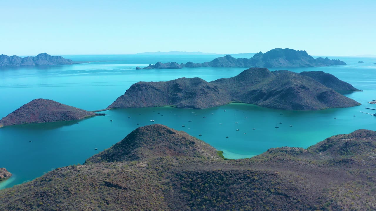 Aerial bay view with rocky foreground slope and small boats.
