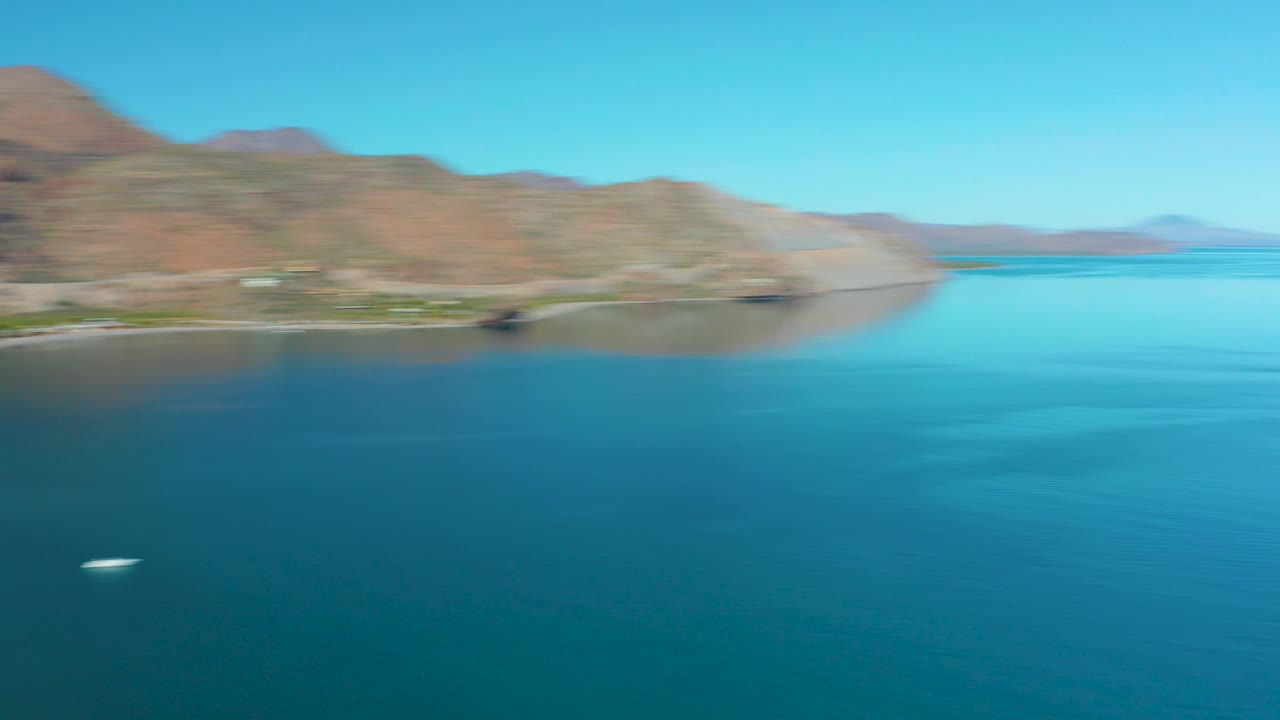 Blurred aerial view of blue water, shoreline, and mountains