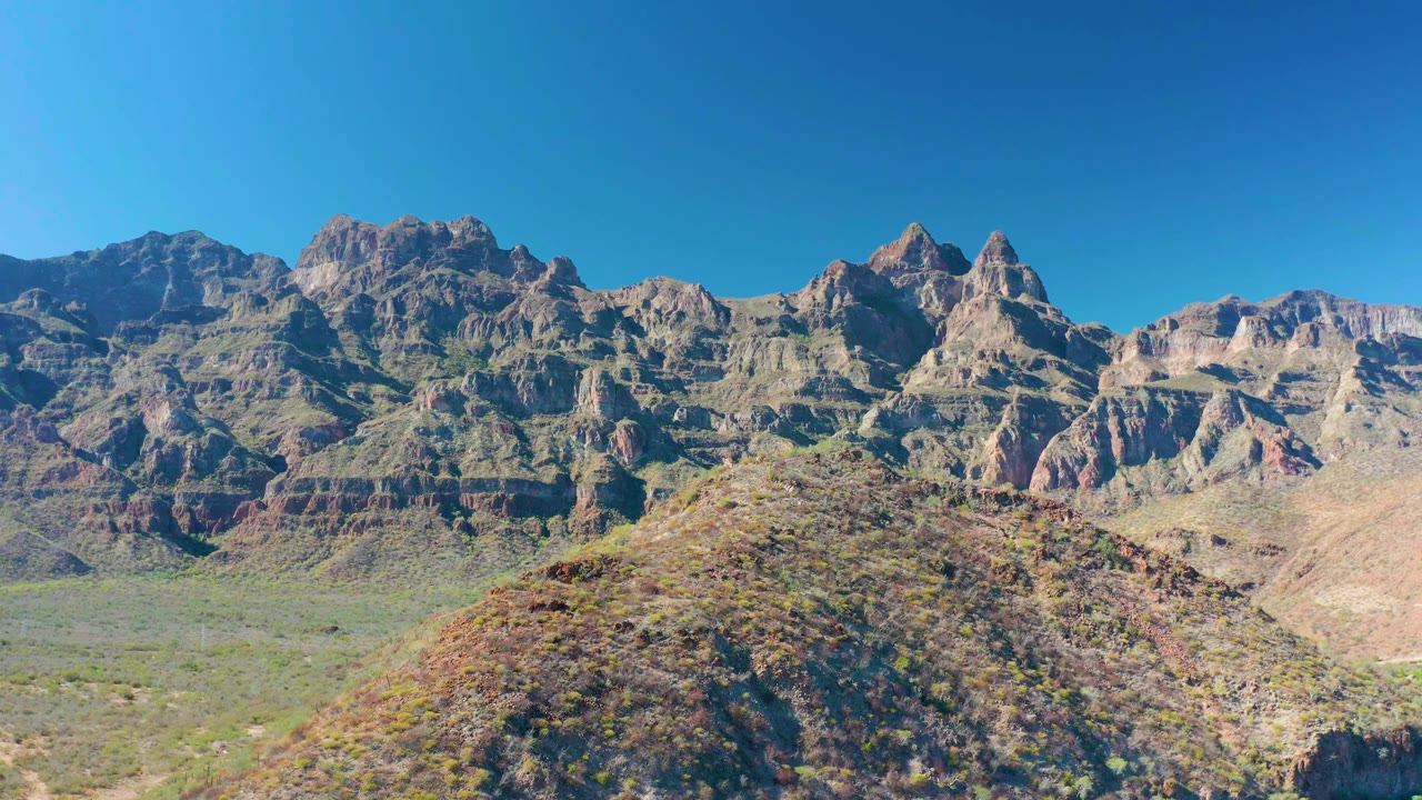 Rugged rock ridges and desert hill in bright daylight.