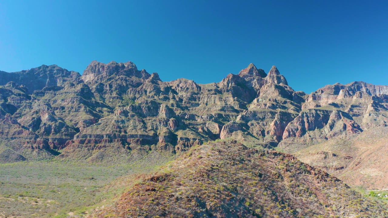 Mid-clip frame of sunlit arid hills and layered mountains in Juncalito, Baja California Sur, with no visible people or structures.