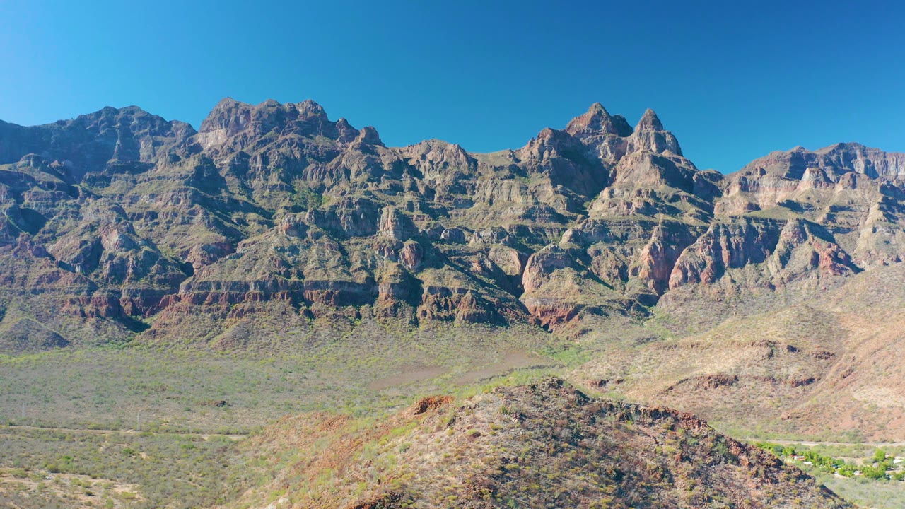 Central runtime frame showing the Baja California Sur mountain wall, sparse desert vegetation, a rounded foreground ridge, and no visible people.