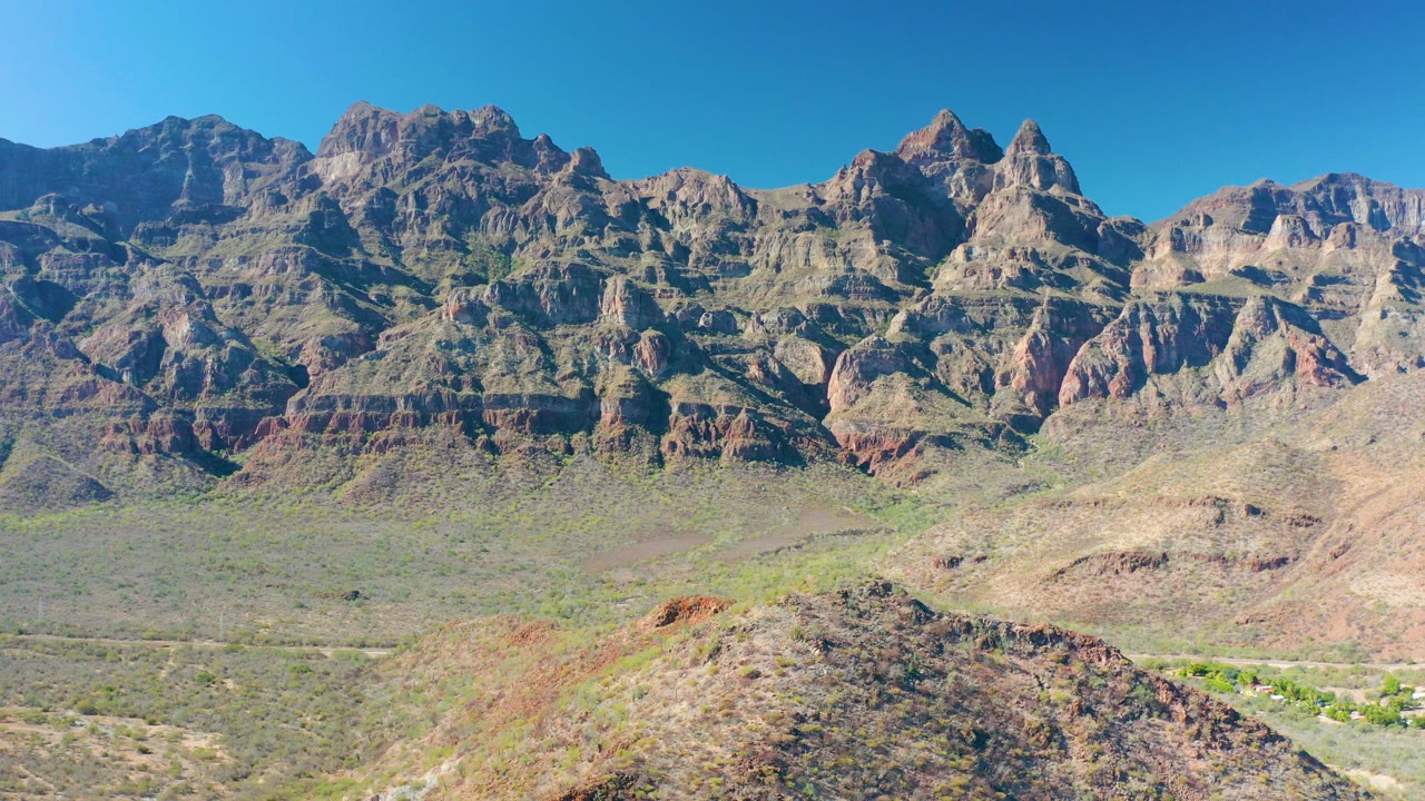 Rugged layered mountains above an arid valley and foreground ridge