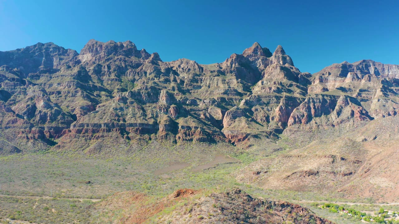Wide desert valley and rugged mountain strata in bright daylight.