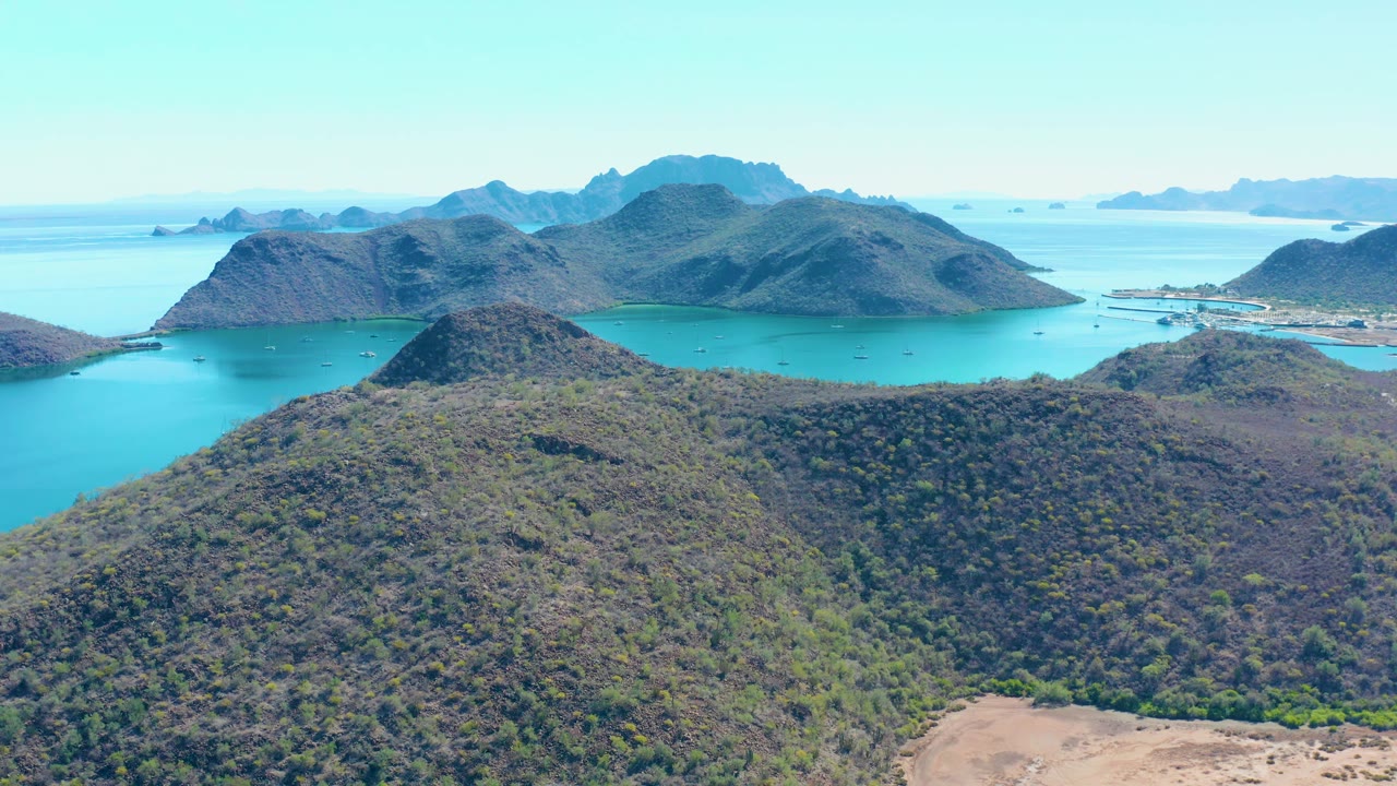 Aerial coastline with hills, bay water, and distant islands