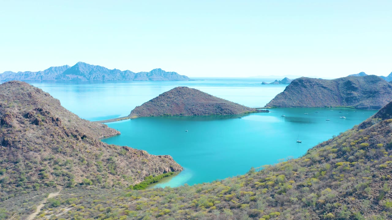 Wide aerial bay view with rocky slopes and boats