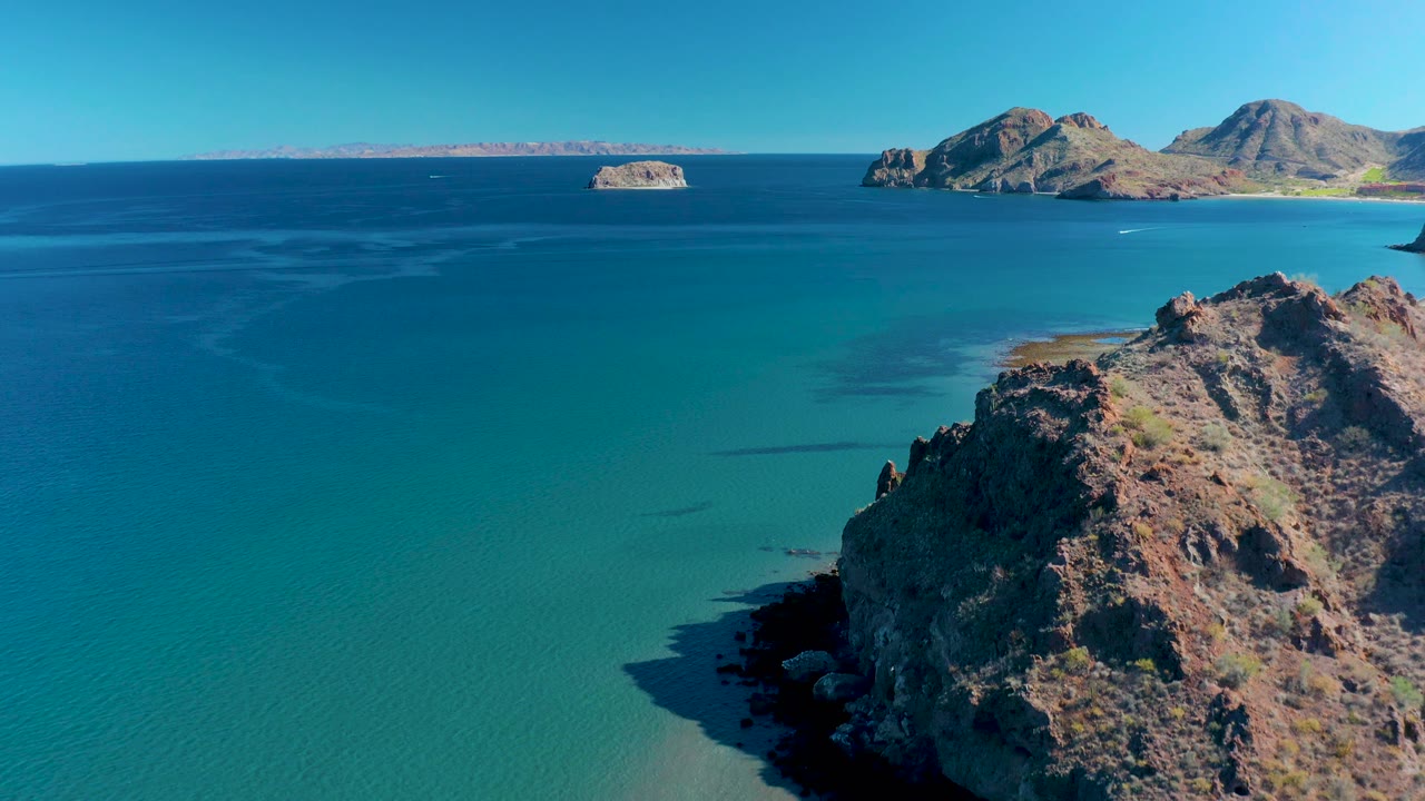 Turquoise bay with rocky cliff and distant islands