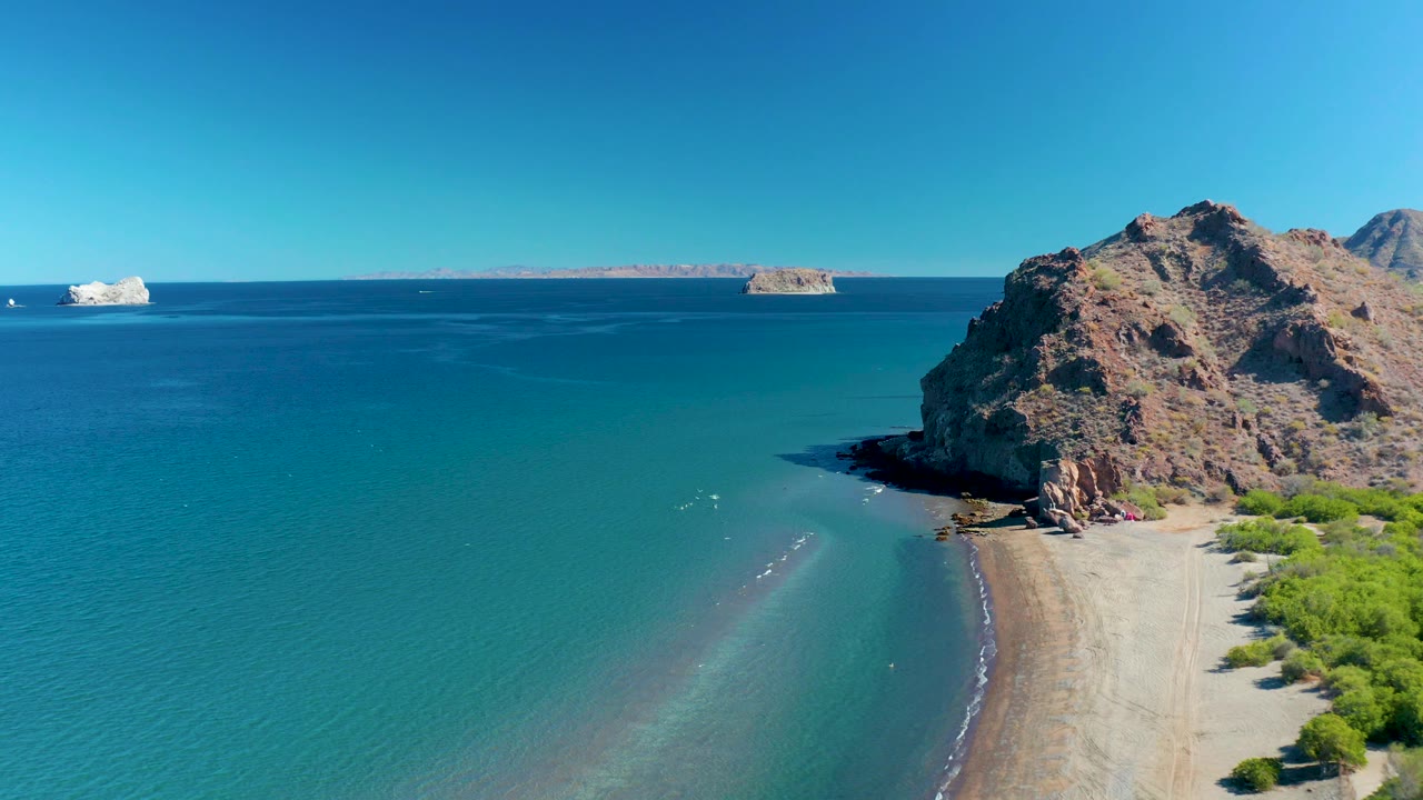 Aerial coastal view with cliff shadow, sandy beach, and open ocean.