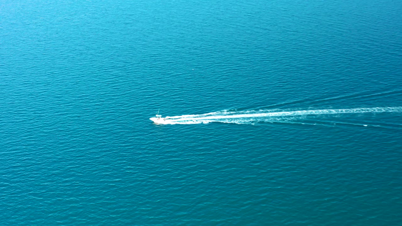 At 0:01 in Ligui, Baja California Sur, the speedboat sits farther across the blue water while its white wake stretches longer behind it, with no visible people.