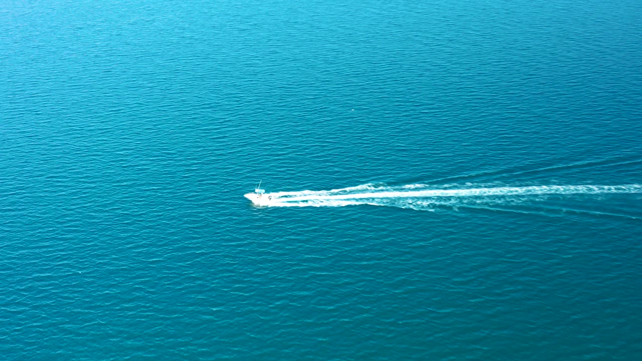 At 0:02 in Ligui, Baja California Sur, the boat runs near the top of the frame as the white wake fans through calm blue ocean, with no visible people.