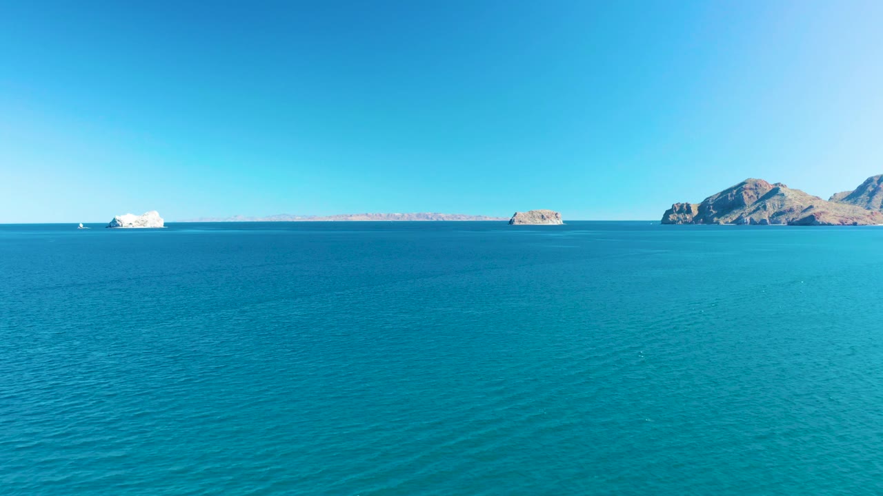 At 0:02, the foreground water texture is prominent, while rocky islands and a pale distant shoreline remain small on the Ligui horizon with no visible people.