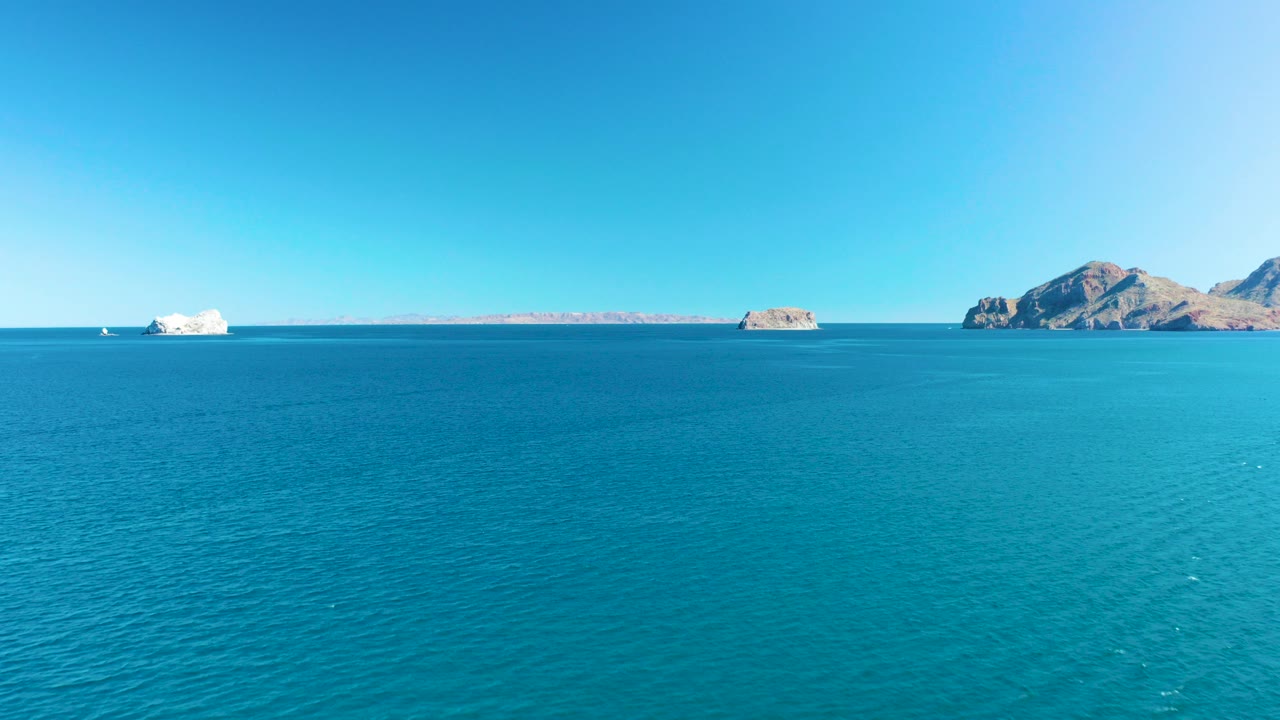 Wide view over turquoise ocean in Ligui, Baja California Sur, with distant rocky islands on the horizon and no visible people.