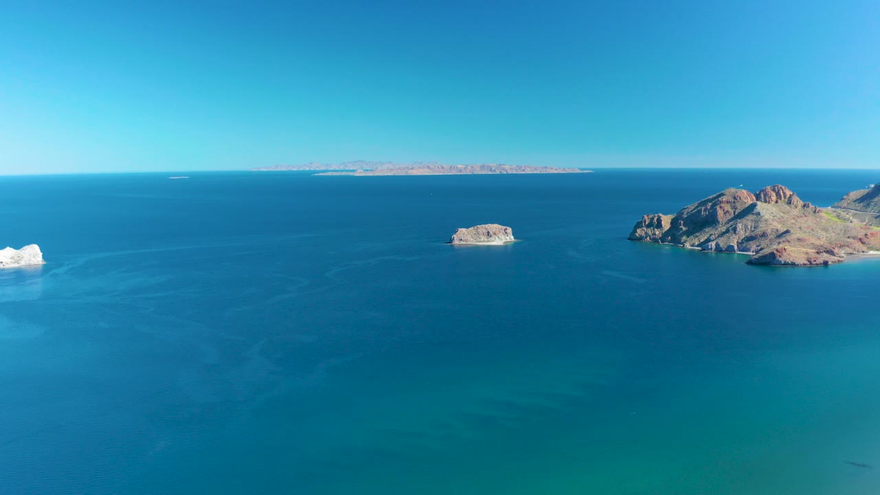 Opening frame of rocky islands off Ligui, Baja California Sur, with blue ocean in the foreground, a distant landmass on the horizon, and no visible people.