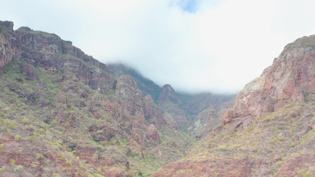 Mountain valley slopes partly covered by cloud