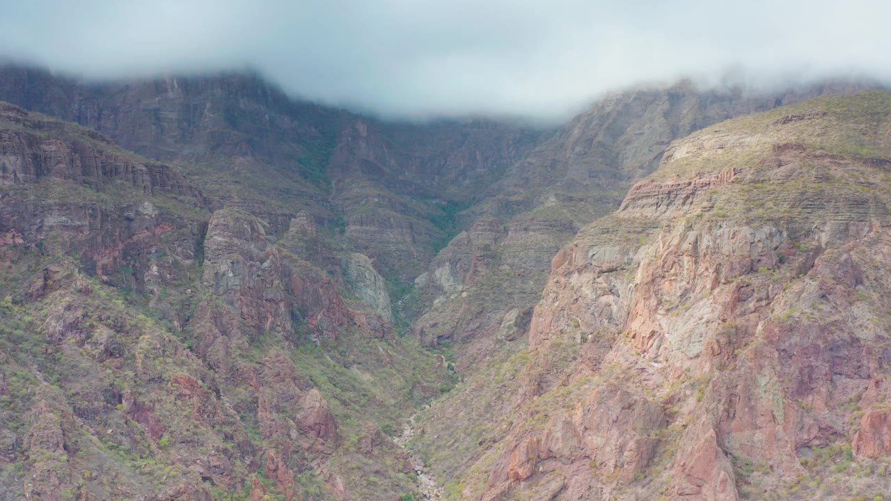 Opening frame of a rocky mountain valley in Puerto Escondido, Baja California Sur, Mexico, with low clouds covering the upper ridges and no visible people.