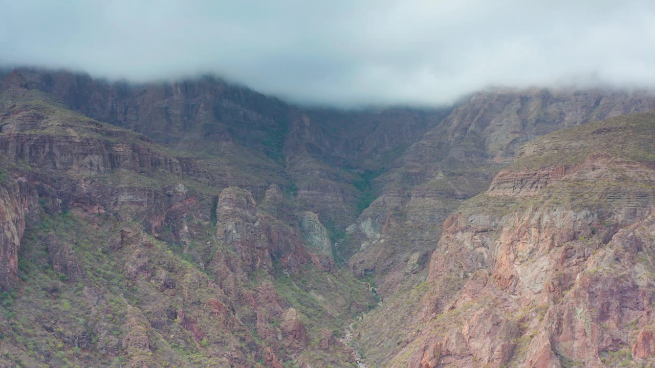 Overcast mountain valley with cloud-covered ridges.