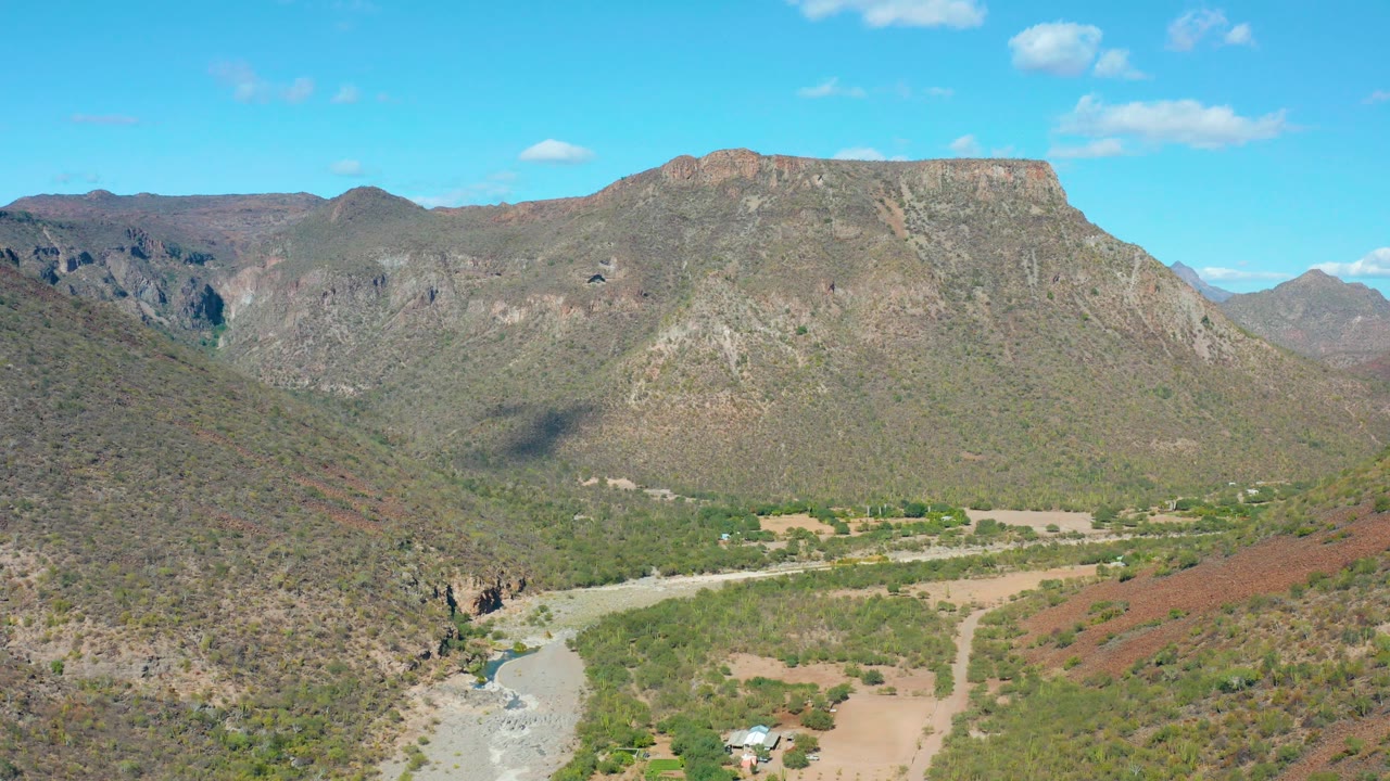 Static aerial view of rocky valley, riverbed, and mountain plateau.