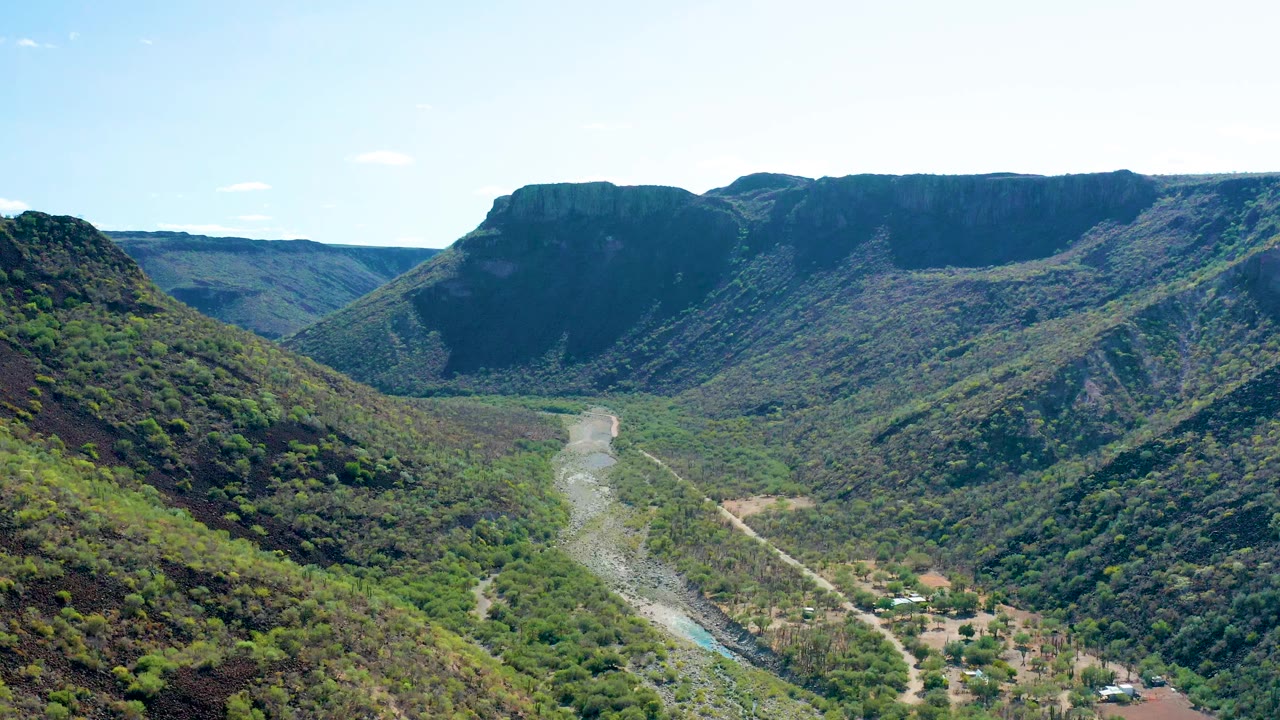 Aerial valley view with river and flat ridge in the background.