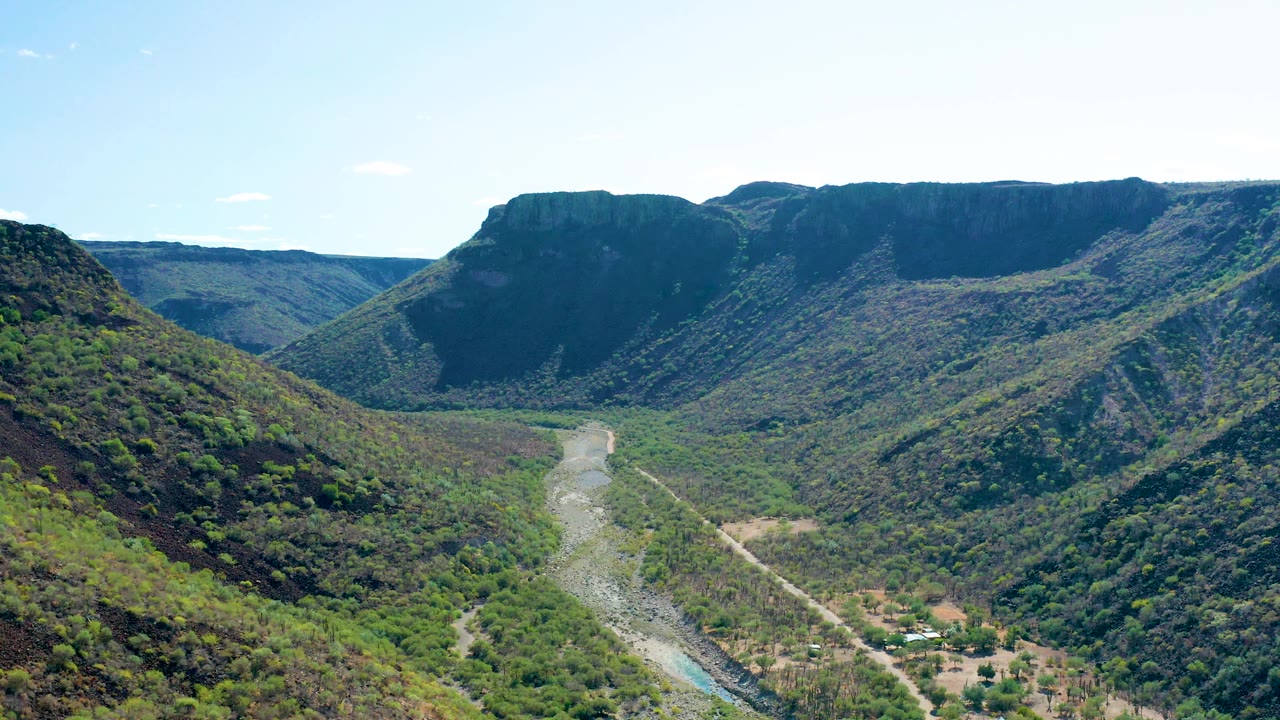 San Javier valley view with a broad flat-topped mountain ridge in back, green slopes on both sides, river and road below, and no visible people.