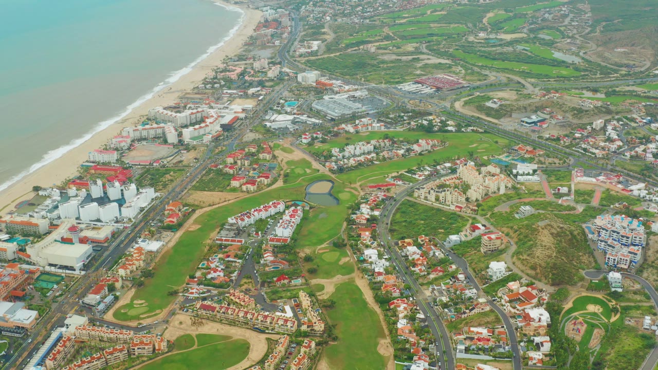 Coastal neighborhood aerial with golf course and beach visible.