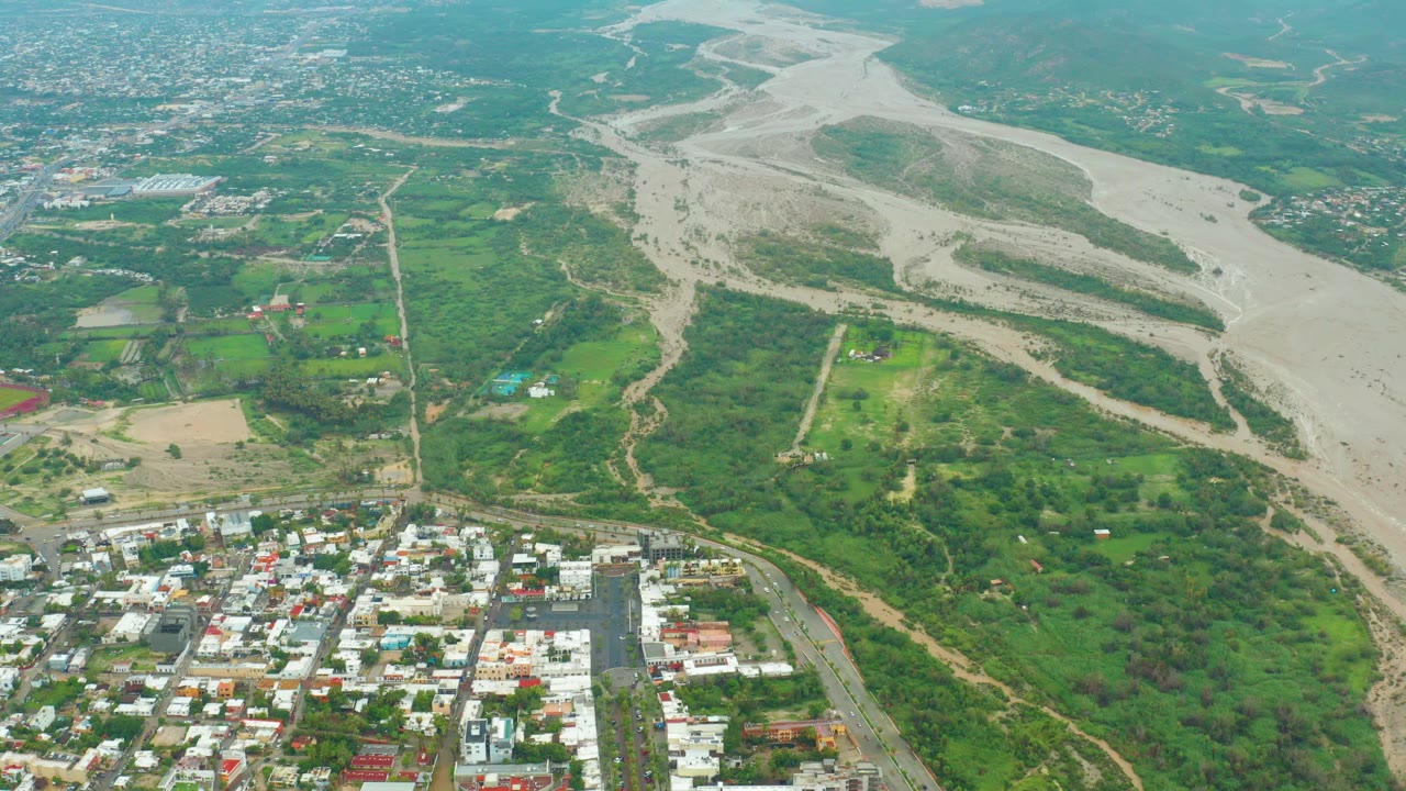 Aerial landscape with green fields beside a wide dry riverbed