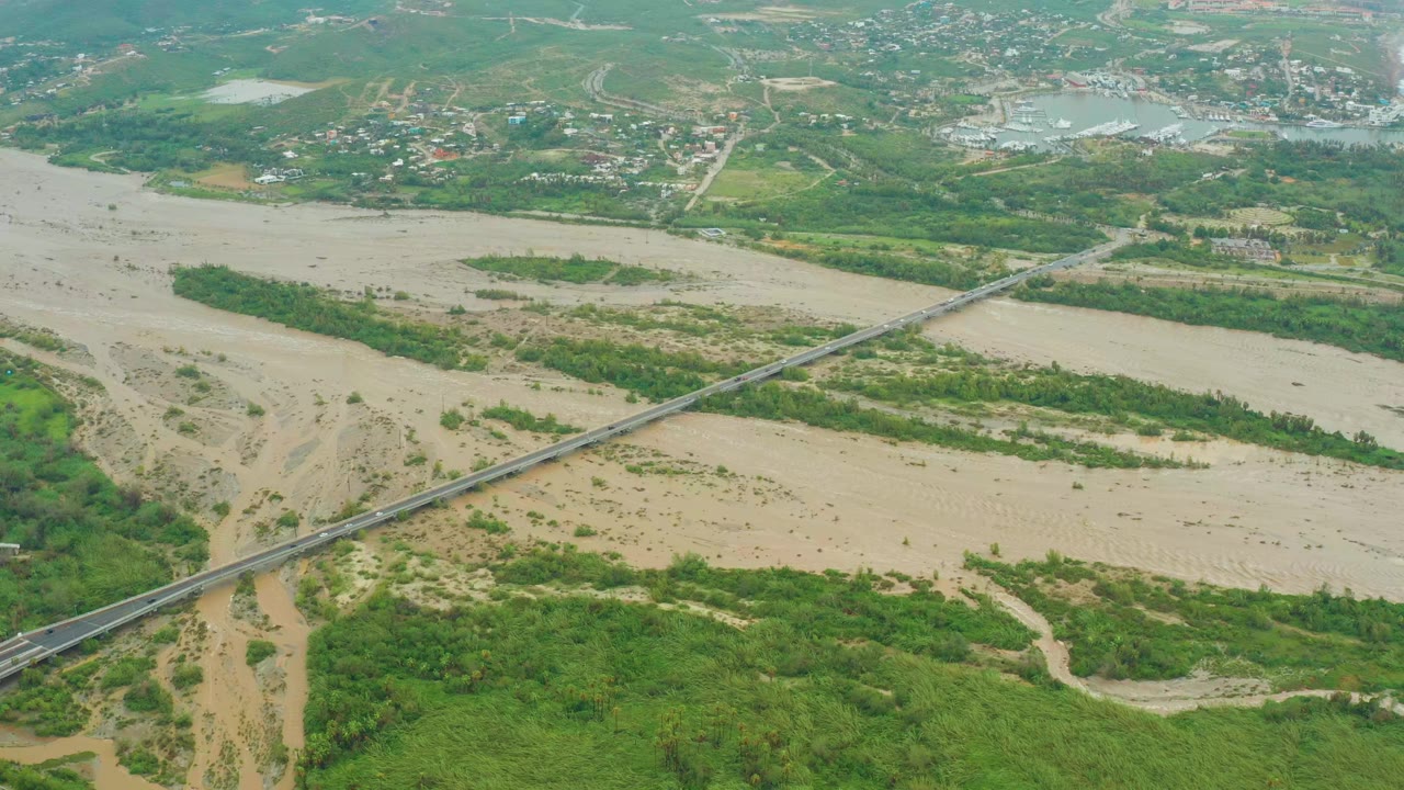 Elevated view of a bridge over muddy water and green riverbank.