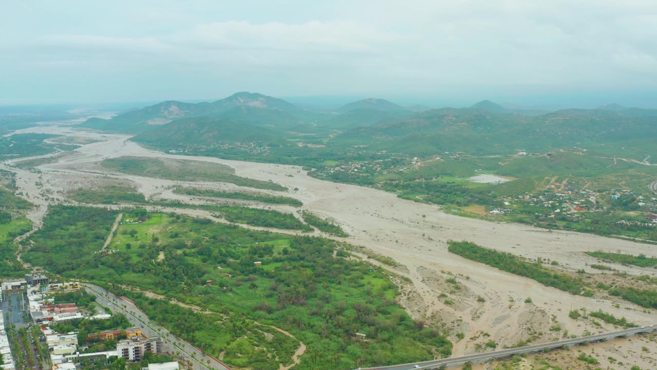 Wide river valley with sediment-colored water and hills in the distance.