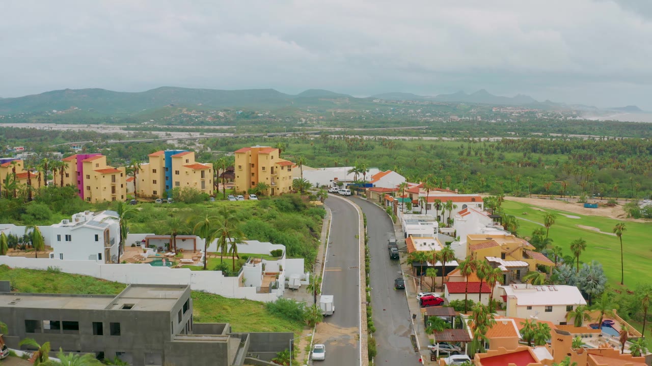 Residential road descending through homes with a white van and distant mountain backdrop.
