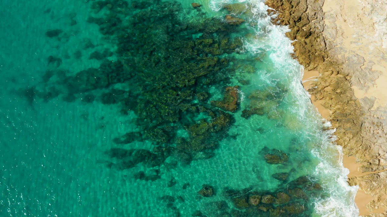 Overhead turquoise water beside a rocky sandy shoreline