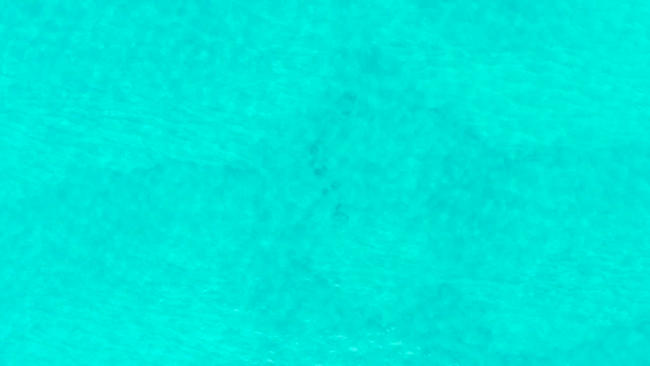 Blue-green shallow water at Laguna Beach Los Cabos shows slightly shifted ripple lines and muted darker areas beneath the surface, with no visible people.