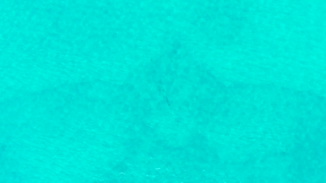 Turquoise ocean surface at Laguna Beach Los Cabos shows mottled darker seabed areas beneath the water, with no visible people.