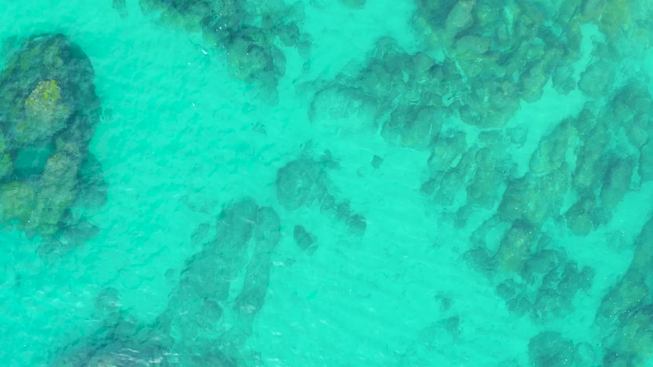 Rock formations visible under blue-green water