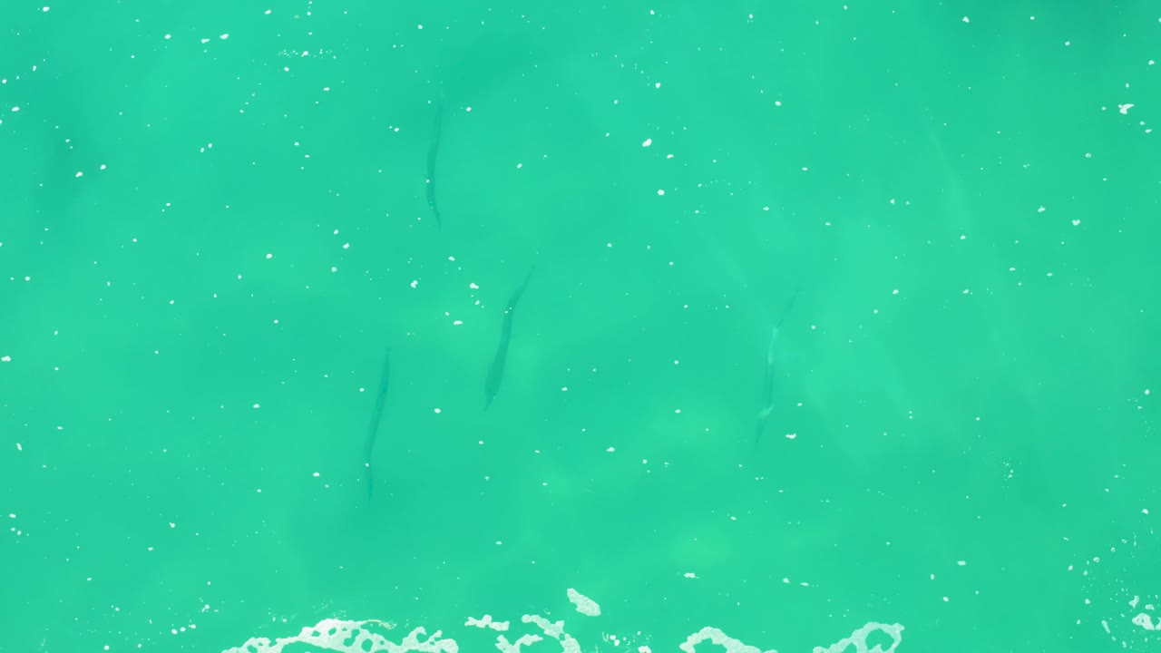 Turquoise water with thin white foam streaks and small bubbles.
